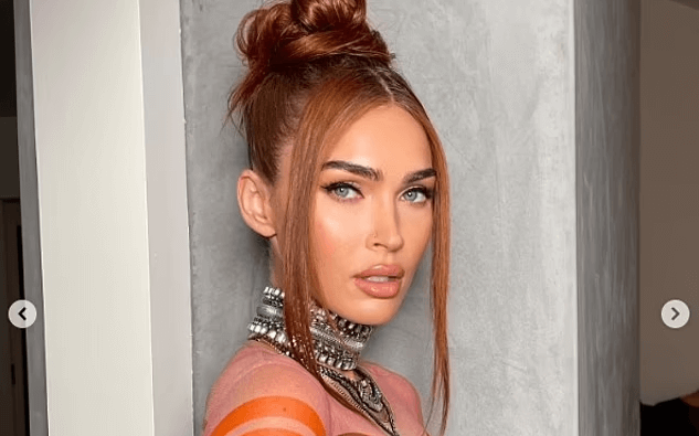 In sultry new snaps, Megan Fox shows off her ample assets in a see-through orange dress