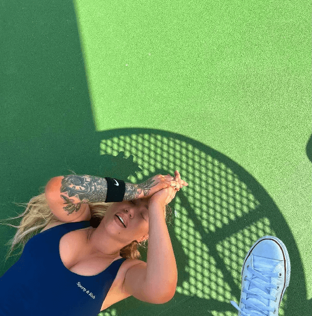 Iggy lay down on the astroturf with her arms covering her face, a Nike sweatband wrapped around her wrist and blonde curls all over the ground.