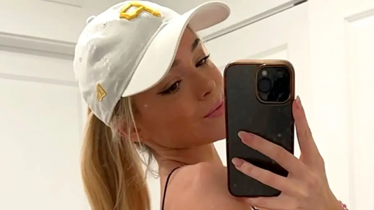 Olivia Dunne looks stunning in a mirror selfie wearing a fitted crop top, light wash jeans and a baseball cap