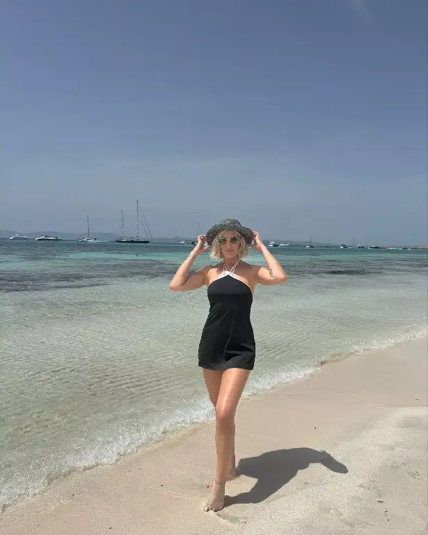 On her trip to Ibiza, she wore a black two-piece braceleted with thin metal straps, looping her bra into a halter-neck and tying her tiny thong on top of her hips.