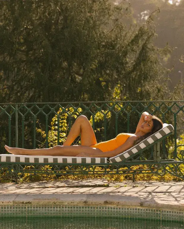 The gorgeous Luisinha Oliveira stuns in an orange swimsuit while lying on a sun lounger