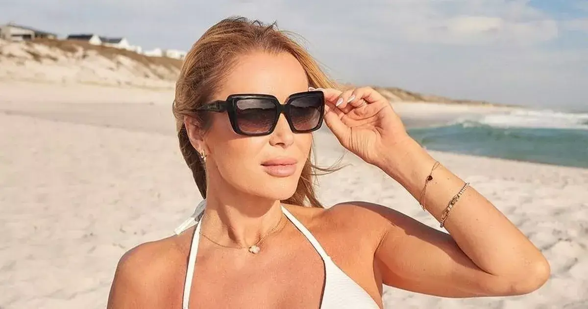 The stunning Amanda Holden, 53, flaunts cleavage in a tiny white bikini when she frolics on the beach