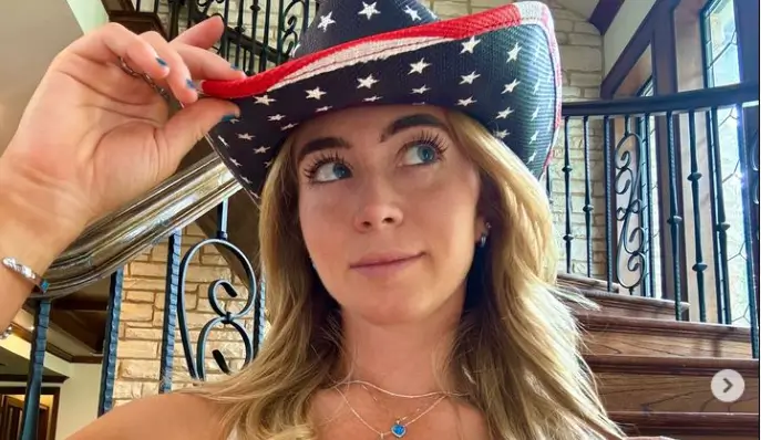 With a low-cut white crop top and star-spangled cowboy hat, Grace Charis leaves little to the imagination