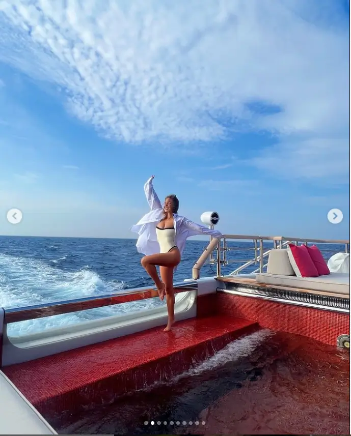 In one snapshot, she was wearing a low-cut white swimsuit with a white shirt as she stood by the swimming pool on board a yacht.