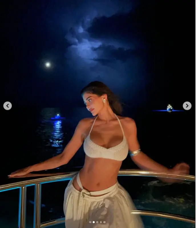 With silver costume earrings and a matching wristband, Jenner accessorized her look with a white mesh knit bikini top and a billowy white skirt.