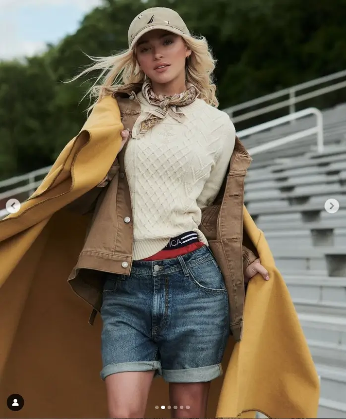 In a second photo, Olivia posed outdoors while wearing a smart cream sweater, a tan jacket, and a yellow blanket forming a cape as she wore her shorts.