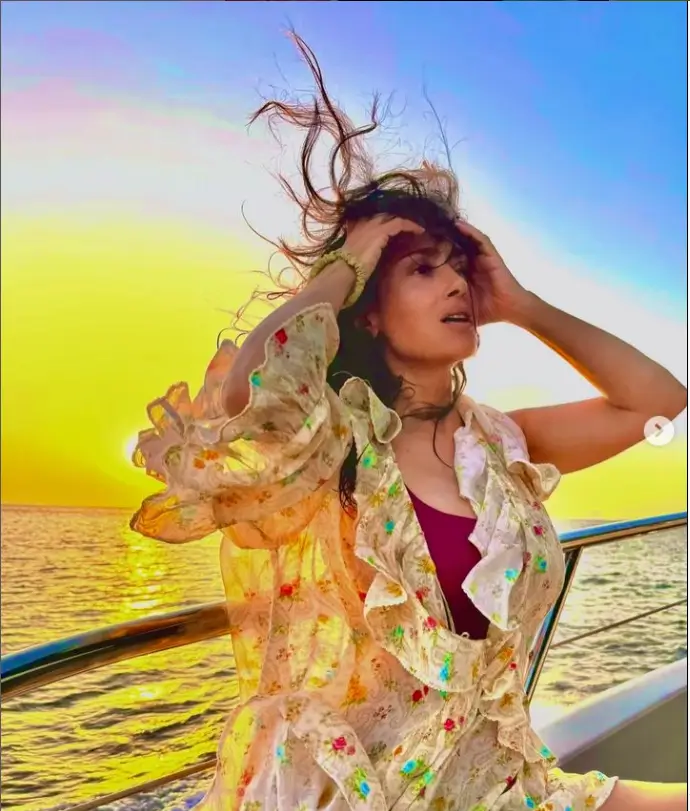 As the sun set over the ocean, Salma wore a gauzy golden coverup adorned with pink, blue, and yellow flowers. She looked serene in the photo.