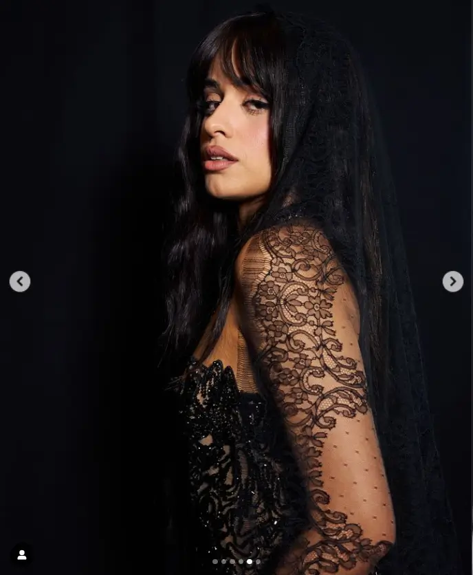 Camila's dress had a serrated, asymmetrical neckline that allowed her to hint subtly at her cleavage underneath the matching black lace veil that draped over her head.