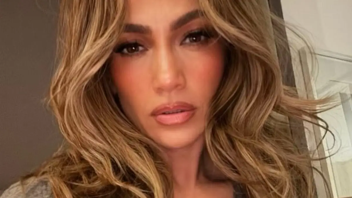 In a low-cut bathrobe, Jennifer Lopez flashed toned abs and cleavage while letting her makeup team highlight her chest with shimmering bronzer.