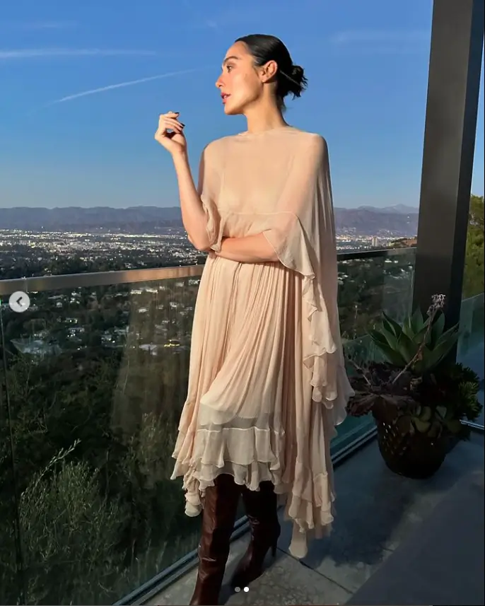 Gal Gadot wore a loose-flowing cream gown that showcased her slim figure while she stood on a balcony