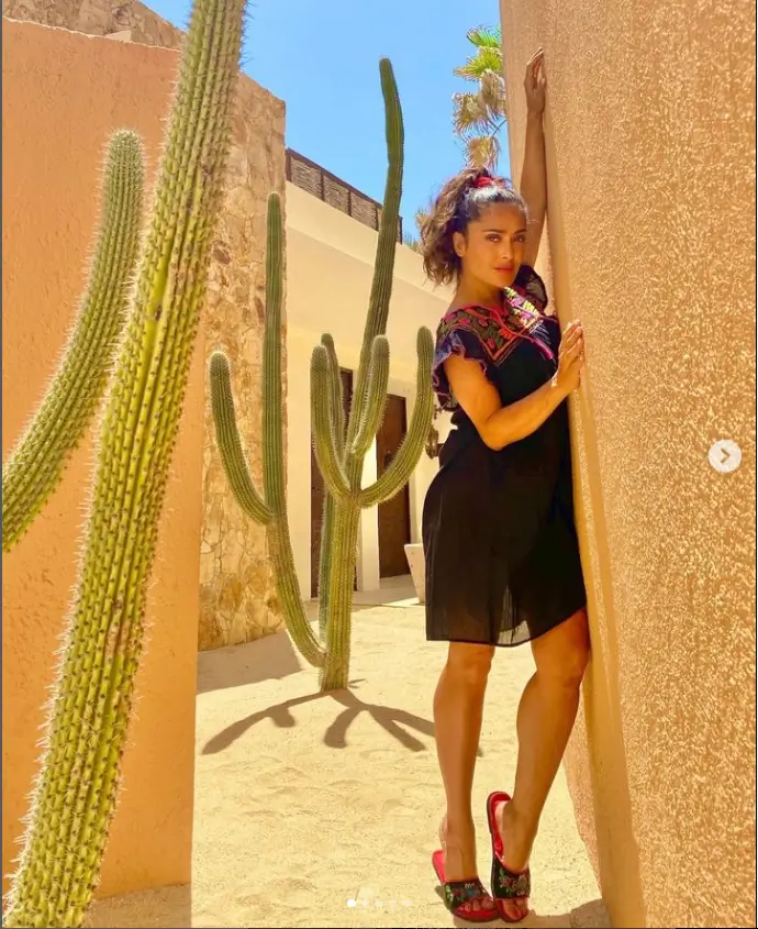 She can be seen in two images leaning against the wall of an orange-brown building while holding a large cactus plant,