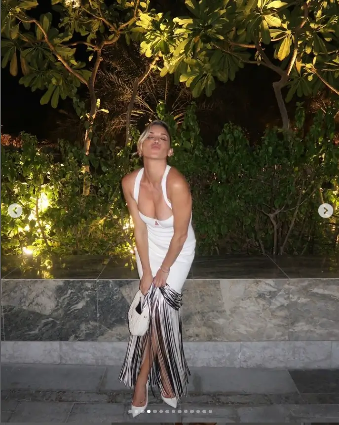 After that, Ashley donned a white midi dress that hugged her enviable figure with black and white fringe along the hemline and a plunging neckline. Her outfit was completed with white pointed heels, a white bag, and simple gold jewellery.