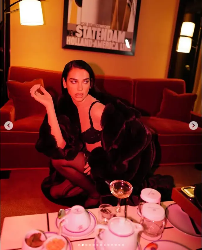 Dua Lipa confidently posed for bold new photos while sipping on a cocktail, showing off her seductive side in black underwear and stockings.