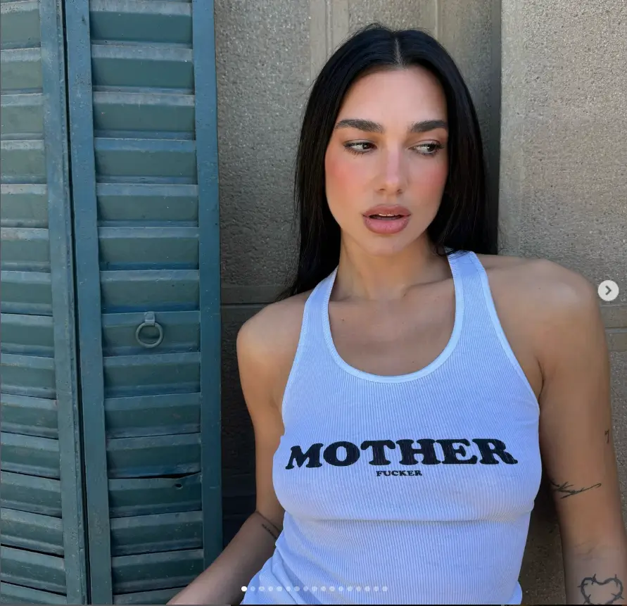 Dua Lipa looked stunning as she showcased her slender physique in a revealing tank top without a bra adorned with bold black lettering.