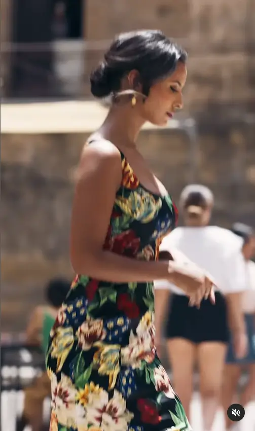 In a stunning Dolce & Gabbana perfume advert, Maya Jama showcases her beautiful figure in a sophisticated and form-fitting floral dress. The ad highlights the actress's style and elegance as she flaunts the brand's latest fragrance.