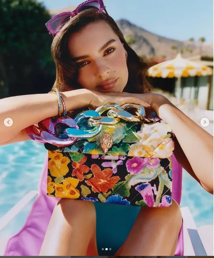 While waist-deep in an outdoor pool, Emily showed off her toned abs and cleavage as she held up a luxurious Kurt Geiger purse for the perfect Instagram photo.