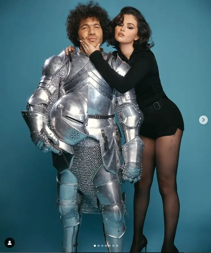 In a different image from the photo shoot, Benny transformed into a brave knight while Gomez gracefully placed her hand under his chin. She looked stunning in a form-fitting, long-sleeved black bodysuit held together by a sleek black belt cinched at her lower waist.