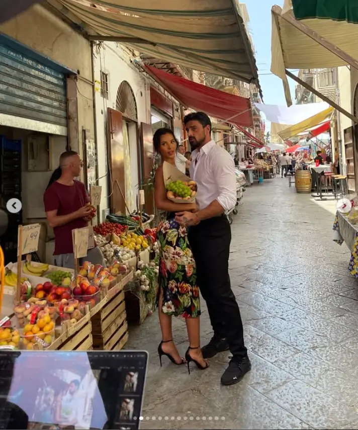 In a captivating scene, Michele and Maya are seen walking hand in hand through bustling village streets, exuding a natural and electrifying chemistry.