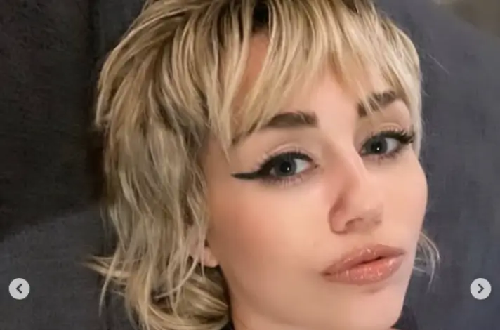 Miley Cyrus  shows off plenty of sideboob in a low-cut bodysuit as she leaning back with a soft smile